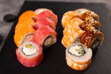 Karanlık arka planda suşi yuvarlanıyor. Japon ve Asya yemekleri