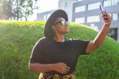 Çekici Afrikalı kadın sokakta selfie çekiyor. Gözlük takıyor. Bin yıllık ve Z kuşağı.