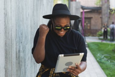 Güzel Afro-Amerikan kadın dijital tablet kullanıyor, açık havada film izliyor. Başarılı blogger etkileyicisi video akışı, iletişim çevrimiçi