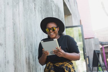 Genç Afrikalı Amerikalı kadın sosyal ağları taramak için tablet kullanıyor. Blog yazarı ve internette blog yazarı. Yaşam tarzı ve dostça