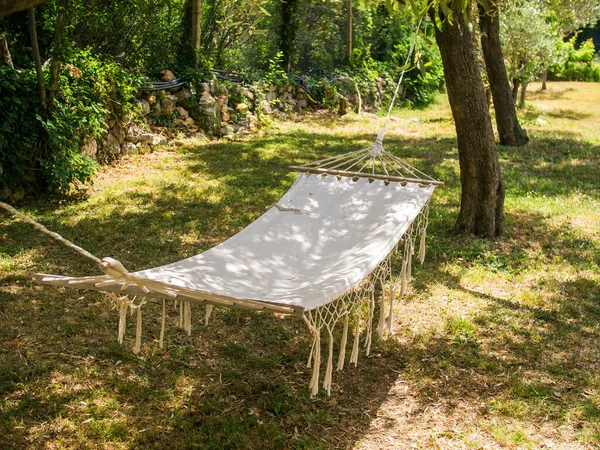 White hammock hanging under tree in countryside - cottagecore and village