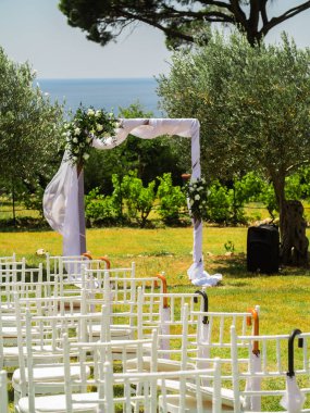 Düğün kemeri dışarıda kumaş ve çiçeklerle süslenmiş. Güzel bir düğün hazırlığı. Bahçedeki yeşil çimlerde düğün töreni. Festival dekorunun bir parçası, çiçek aranjmanı..