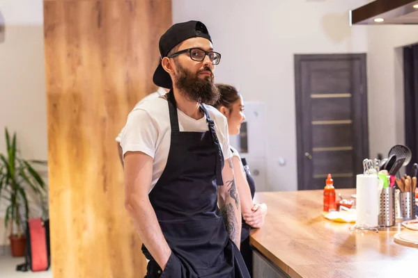 stock image Happy confident young waiter entrepreneur looking at camera, smiling male small cafe business owner employee standing in restaurant, millennial businessman wear apron posing in coffee shop portrait