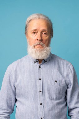 Portrait of unhappy grumpy pissed off senior mature man blue background. Negative human emotions, face expression feelings
