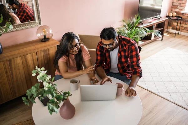 Latino or indian man and woman couple use their laptop in the living room to make video calls. Video call and online chat with familys