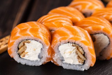 Sushi roll philadelphia with salmon and cucumber and cream cheese on black background. Sushi menu. Japanese food