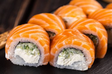 Sushi roll philadelphia with salmon and cucumber and cream cheese on black background. Sushi menu. Japanese food