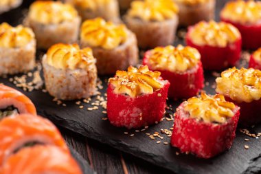 Large sushi set from top on black background. Assortment of various maki nigiri and rolls seafood soy sauce