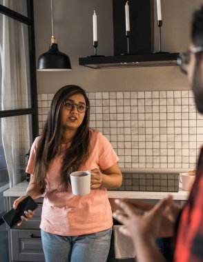 Indian woman talking to latino man in the kitchen. Lifestyle, healthy eating, multi ethnic