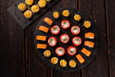 Large sushi set from top on black background. Assortment of various maki nigiri and rolls seafood soy sauce