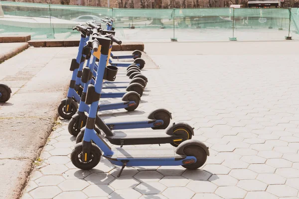 都市に停められた電動スクーターの列 人々の輸送のための近代的なバッテリー駆動のレンタカー 持続可能な都市移動の概念の新しい傾向を概念 — ストック写真
