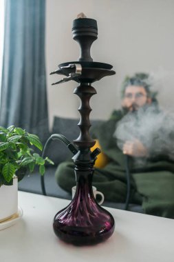 Hookah shisha with glass flask and metal bowl in room background. Traditional Eastern vacation for relaxation.