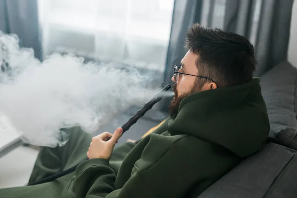 Bearded Millennial Gen Man Smoking Hookah While Relaxing Sofa Home — Stok Foto
