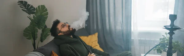 Γενειοφόρος Άνθρωπος Είναι Κάπνισμα Hookah Στο Σπίτι Και Φυσάει Σύννεφο — Φωτογραφία Αρχείου