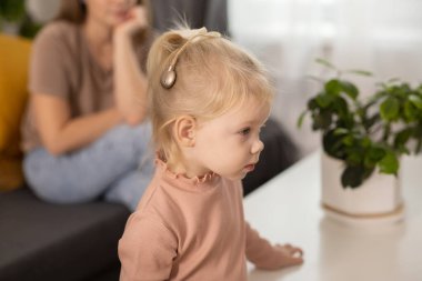 Funny baby with cochlear implant sitting at home and eating. Hear aid and medicine innovating technology and diversity concept