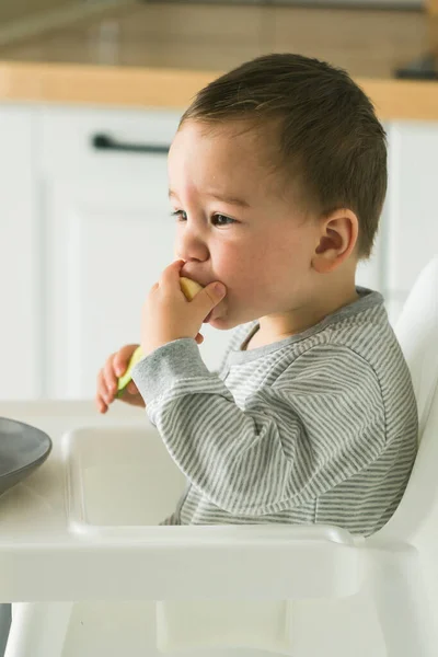 Szczęśliwe Dziecko Siedzące Wysokim Krześle Jedzące Marchewkę Kuchni Zdrowe Odżywianie — Zdjęcie stockowe