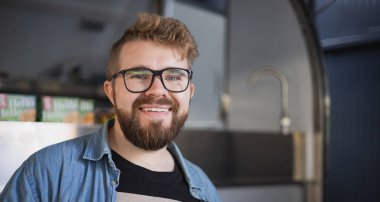 Modern işyerinde gülümseyen genç yaratıcı girişimcinin portresi - ofiste sakallı serbest çalışan bir adam .