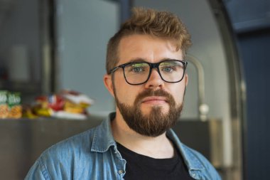Modern işyerinde gülümseyen genç yaratıcı girişimcinin portresi - ofiste sakallı serbest çalışan bir adam .