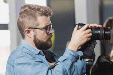 Adam video yapımcısı, basın konferansında modern video kamerada çalışıyor. Dijital ekran, etkinlikle ilgili bir röportajı kaydediyor. Kitle iletişim araçları, televizyon ve teknoloji