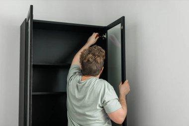 Genç ve çekici bir adam mobilya montajı yapıyor. Hancı ve iç nesneler.