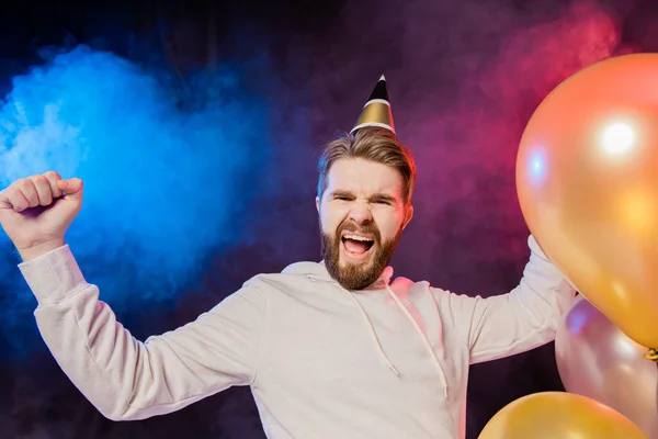 快乐的寿星 头戴纸锥帽 唱歌跳舞 站在五彩缤纷的氦气气球旁 欢欢欢喜喜地庆祝节日和胜利 — 图库照片