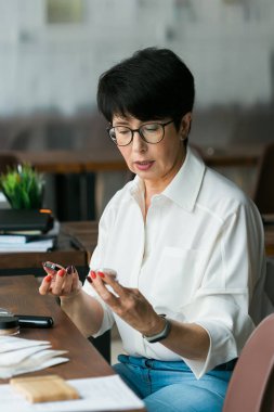 Gülümseyen olgun kadın elinde mineral makyaj tozu tutuyor. Kozmetik ürün.