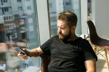 Modaya uygun sakallı adam şık kıyafetler ve moda saç stili giyer. Arkadaşlarla mesajlaşmaktan ve elektronik modern cihazlar üzerinde ücretsiz internet bağlantısı kullanmaktan mutluluk duyarız. Sosyal ağlar ve hayat.