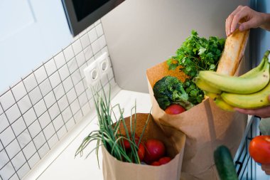 Mutfaktaki sebze ve sebzelerle dolu kağıt alışveriş torbası. İnternet üzerinden alışveriş ve yiyecek konsepti.