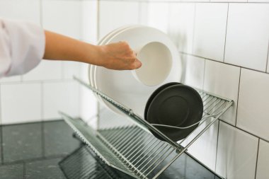 Bulaşık rafına yeni yıkanmış tabağı koyan bir kadın.