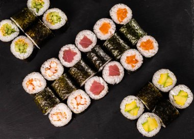 Karanlık arka planda suşi yuvarlanıyor. Japon ve Asya yemekleri