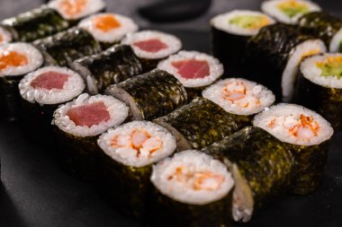 Karanlık arka planda suşi yuvarlanıyor. Japon ve Asya yemekleri