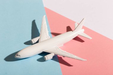 Pastel mavi ve pembe arka planda model uçak. Düz dizayn. Uçuş ve uçak