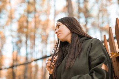 Güzel, gülen bir kadın sonbaharda dışarıda yürüyor.