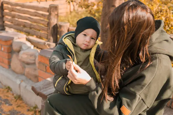 귀여운 소년은 어머니와 있습니다 공원에서 소년은 재킷과 모자를 착용합니다 — 스톡 사진
