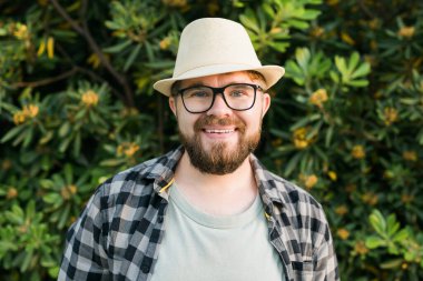 Close up portrait handsome young man over green bush outside copy space and place for advertising