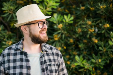 Close up portrait handsome young man over green bush outside copy space and place for advertising