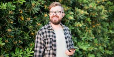 Laughing attractive man wearing hat over green tree background - emotion and vacation travel holidays