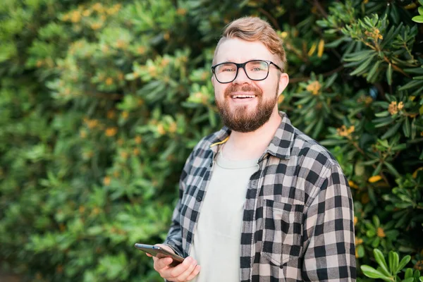 Portrait of attractive cheerful guy using smartphone for scrolling on social media over bright vivid shine vibrant yellow color