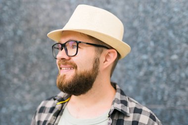 guy tourist looking happy wearing straw hat for travelling, standing against concrete wall background with copy space