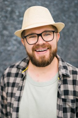guy tourist looking happy wearing straw hat for travelling, standing against concrete wall background with copy space