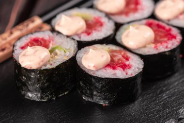 Maki sushi roll with salmon avocado and tobiko caviar served black board close-up - Japanese food