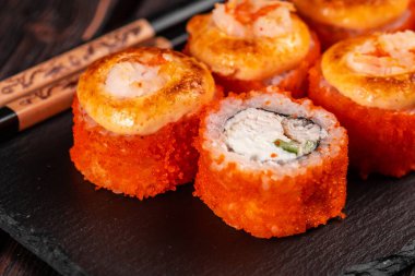 California sushi roll with crab, avocado, cucumber and tobiko caviar served on black board - Japanese food.