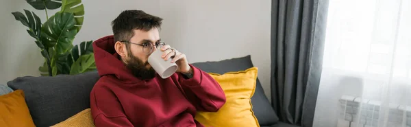 Hombre Árabe Joven Bebiendo Sentado Sofá Casa Banner Espacio Copia —  Fotos de Stock