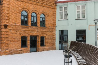 Kasaba merkezinde iki bina ve kış mevsiminde karlı uzun ahşap bank. Mimarlık ve kentsel sahne konsepti