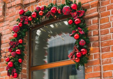 Şehir caddesindeki tatil pazarının önünde kırmızı ve altın mücevherlerle süslenmiş Noel köknar dalları. Kış Noel sokak dekorasyonu