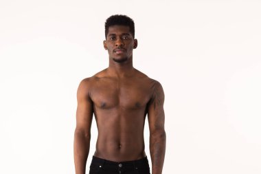 Ciddi bir Afro-Amerikan portresi. Çıplak. Adam beyaz stüdyoya bakıyor.