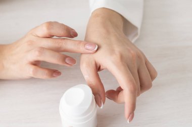 Kremalı kadın elleri. Kadın ellerine krem sürüyor. Avuç içleri pürüzsüz, derileri pürüzsüz, tırnakları doğal.