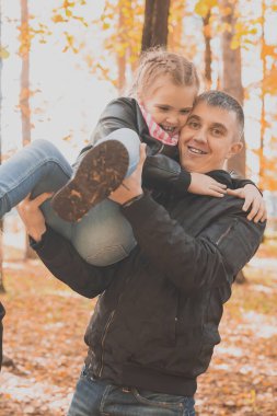 Mutlu bir baba ve kızı güzel bir sonbahar parkında oynayıp eğleniyor. İdeal bir hafta sonu babası ve küçük kızı..