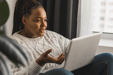 African american woman making video call, in kitchen - social networks
