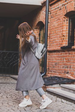 Millennial 'da genç bir kadın şehir sokaklarında eğleniyor ve dans ediyor. Bayan komik arkadaşlar, şehirde sonbahar gününün tadını çıkarıyorlar.